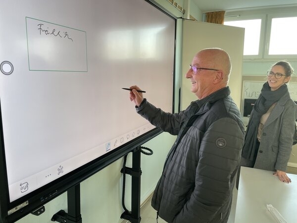 Bild vergr&ouml;&szlig;ern: Peter Fröhlich neben interaktiver Tafel in Ostsee-Schule