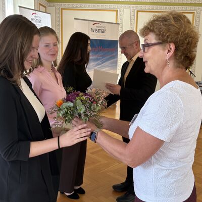 Bild vergr&ouml;&szlig;ern: Birte Weiss (r.) aus dem Amt für Personal, Organisation und IT überreicht Blumen und Bürgermeister Frank Junge die Ausbildungszeugnisse an Lilly Jablinski, Lena Limpack und Lelaina Herzog (v.l.).