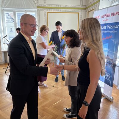 Bild vergr&ouml;&szlig;ern: Bürgermeister Frank Junge überreicht Ausbildungszeugnisse an Lucy Schwanbeck (r.) und Merle Gutsche.
