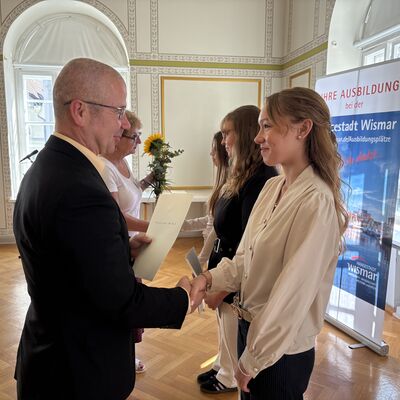 Bild vergr&ouml;&szlig;ern: Birte Weiss aus dem Amt für Personal, Organisation und IT überreicht Blumen und Bürgermeister Frank Junge gratuliert Melina Sulz, Claudia Pust und Emma Borsics (v.r.).
